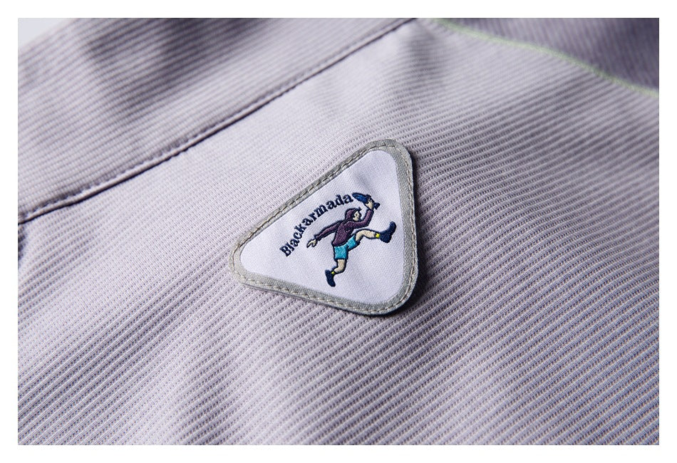 Close-up of a triangular embroidered patch with a running figure on pale lavender-gray ribbed fabric.