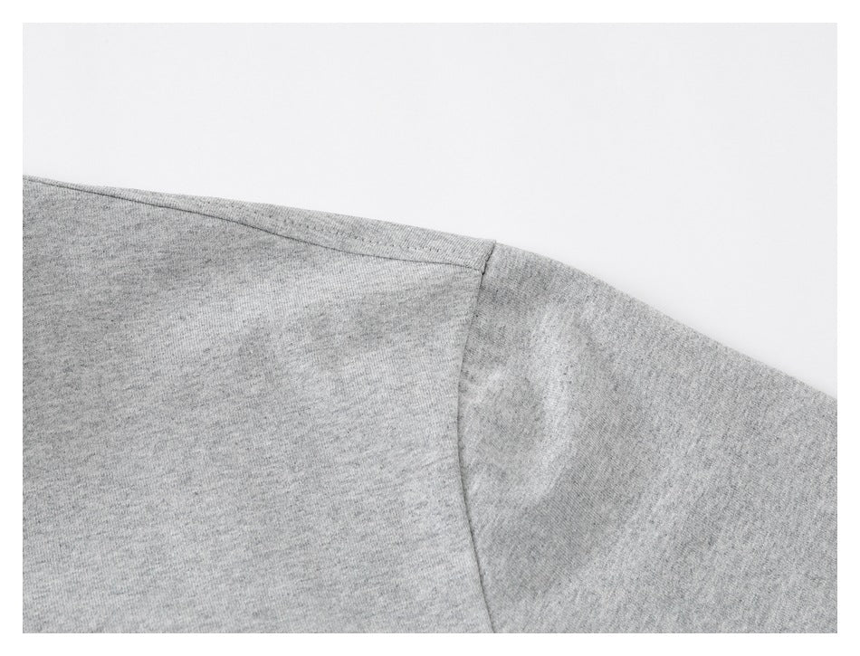 Close-up of the shoulder seam and sleeve seam on a heather-gray T-shirt.