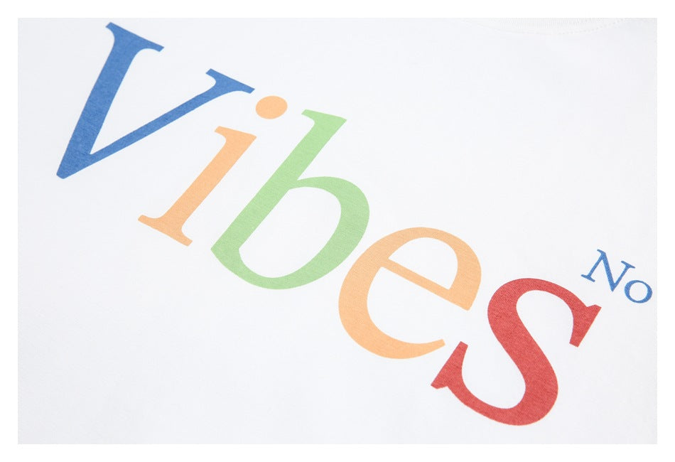 Close-up of the T-shirt’s multicolored “Vibes No” chest print on white fabric.