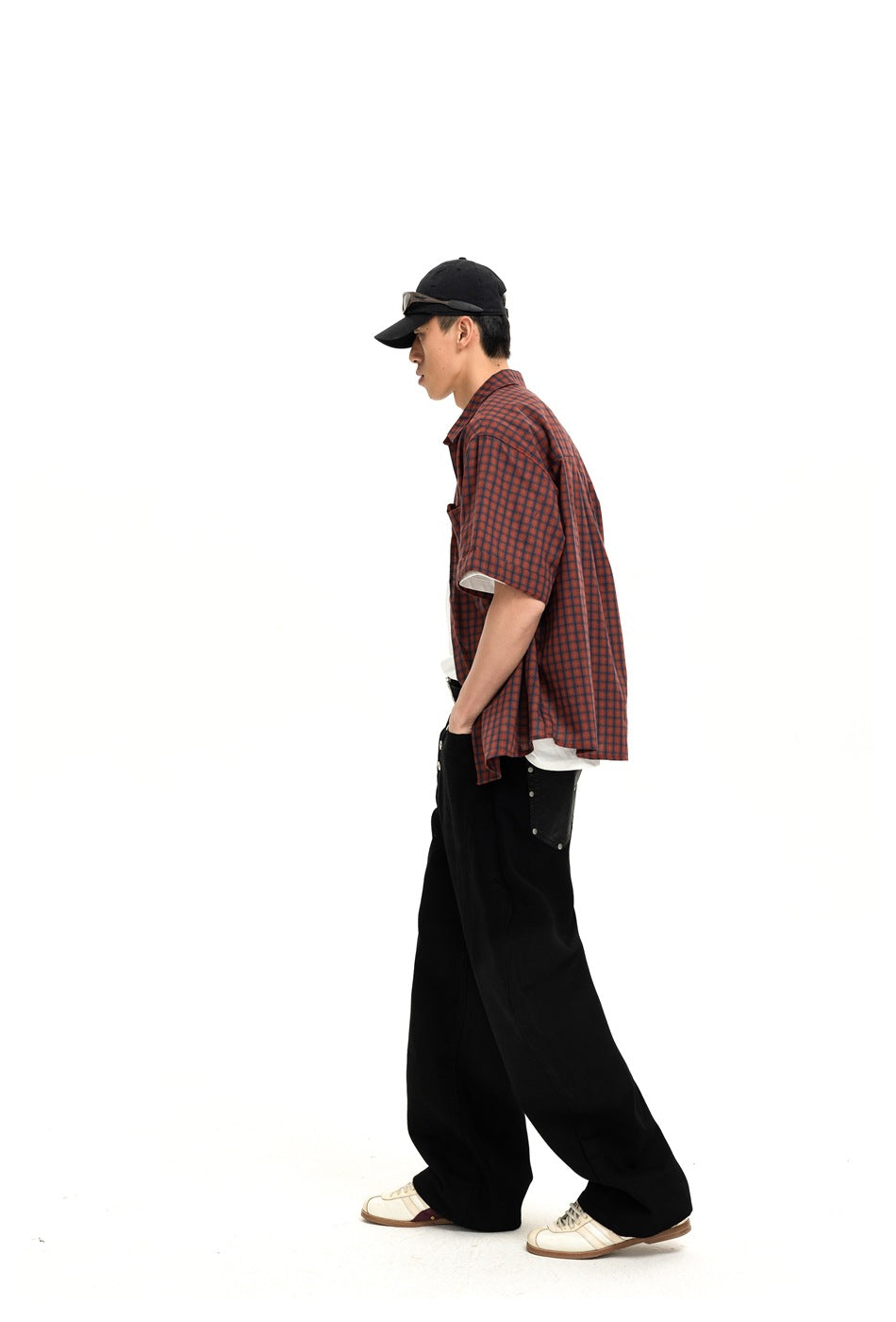 Side view of a model wearing black wide-leg pants with a red-and-black checked shirt.