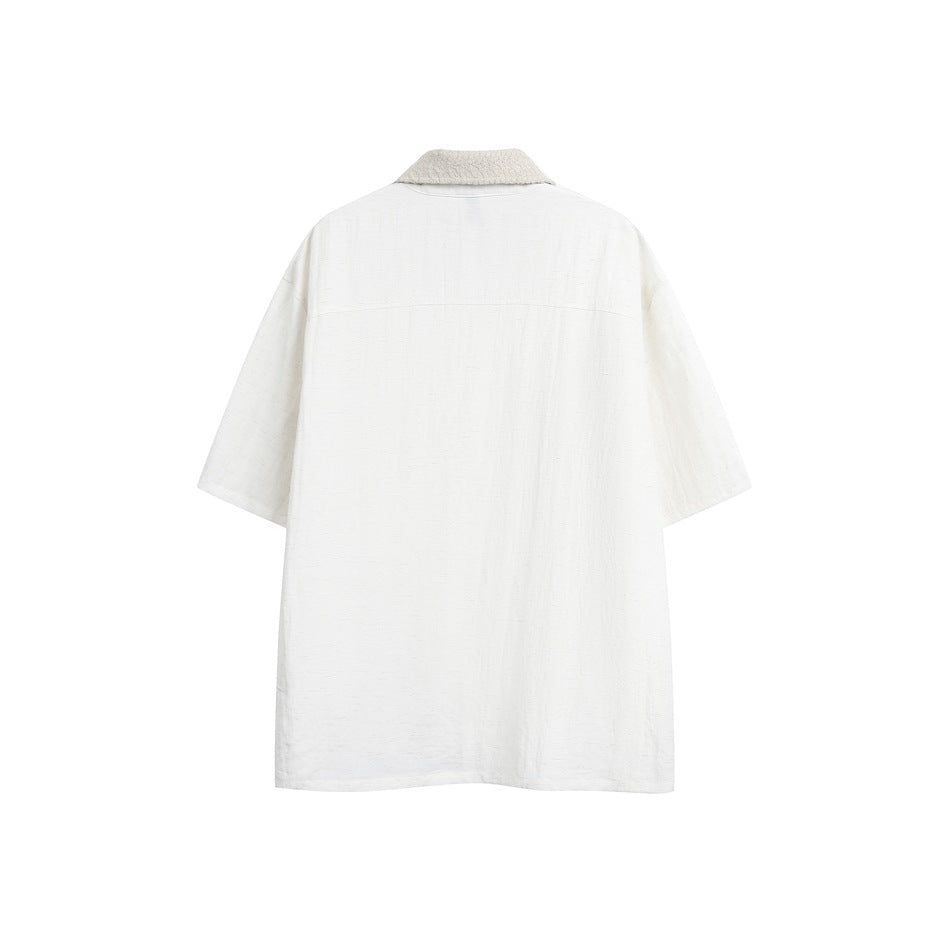Back view of an ivory short-sleeve shirt with a beige textured collar and a horizontal yoke seam.
