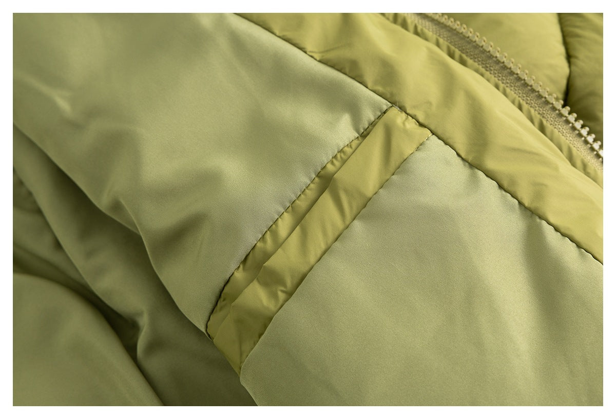 Close-up of an olive-green jacket seam, smooth panel, and edge of the zipper.