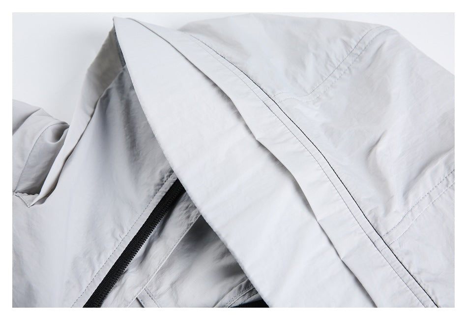 Close-up of a light gray jacket's hood and stitched fabric panels.