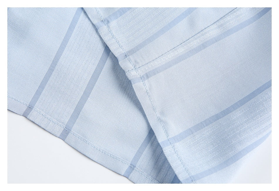 Close-up of intersecting seams and striped fabric on the light blue shirt.