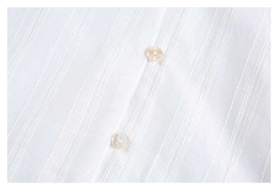 Close-up of two translucent buttons on white fabric with raised vertical stripe detailing.