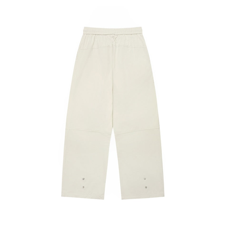 Back view of off-white wide-leg pants with an elastic waistband, yoke seam, and small snaps near the hems.