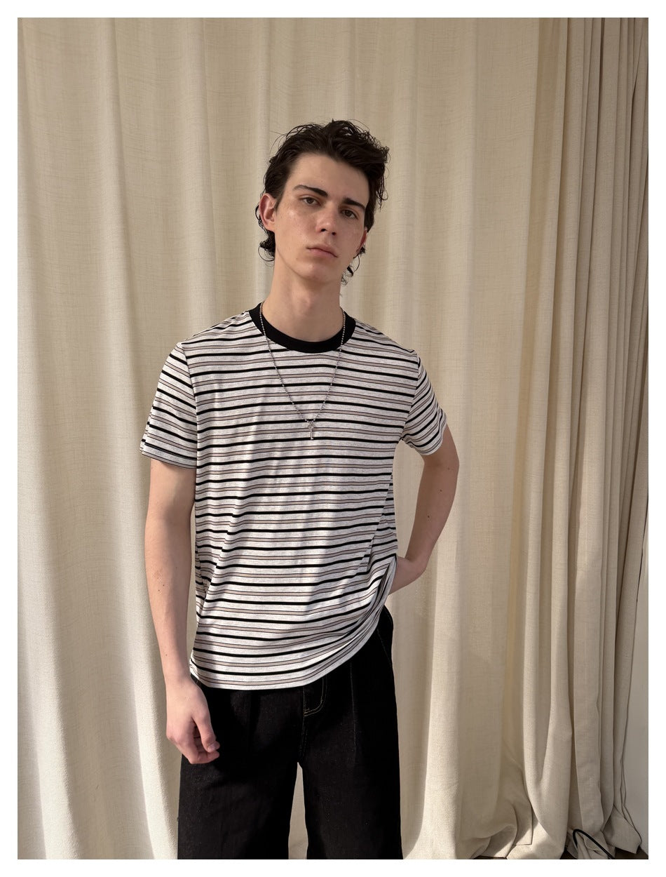 Front view of a model wearing a light gray T-shirt with thin black horizontal stripes and a black crew neck.