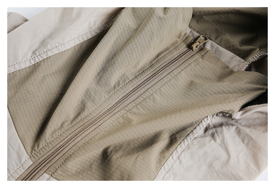 Close-up of the jacket's beige grid-patterned fabric and front zipper.