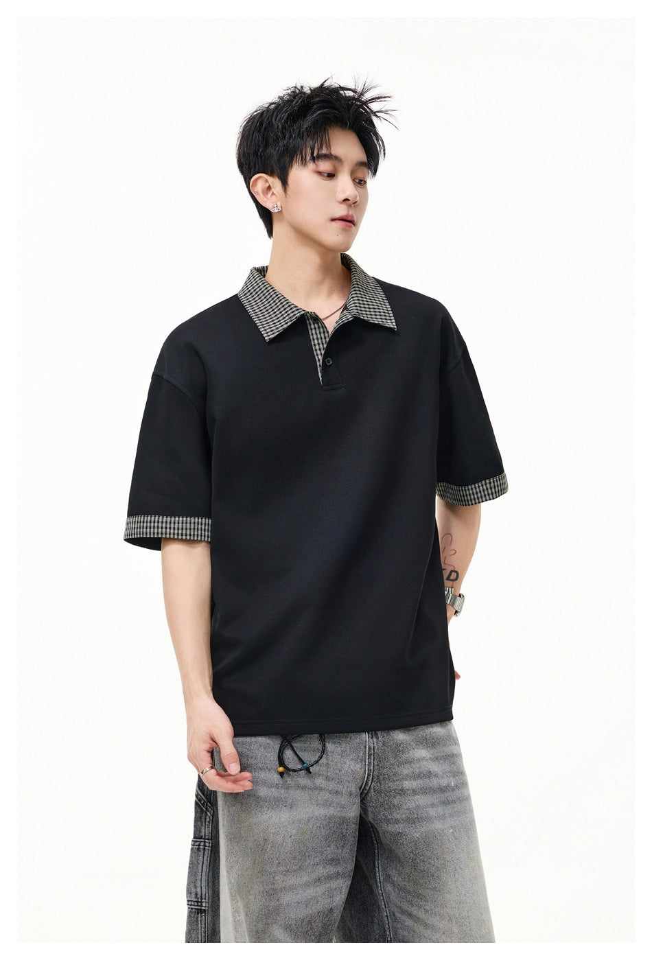 Closer view of a model wearing a black polo with a checked collar, placket trim, and sleeve cuffs.