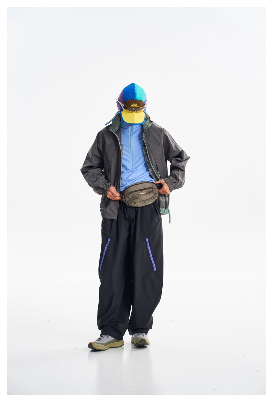 Front view of a model in a charcoal jacket and black trousers, adjusting a waist pack.