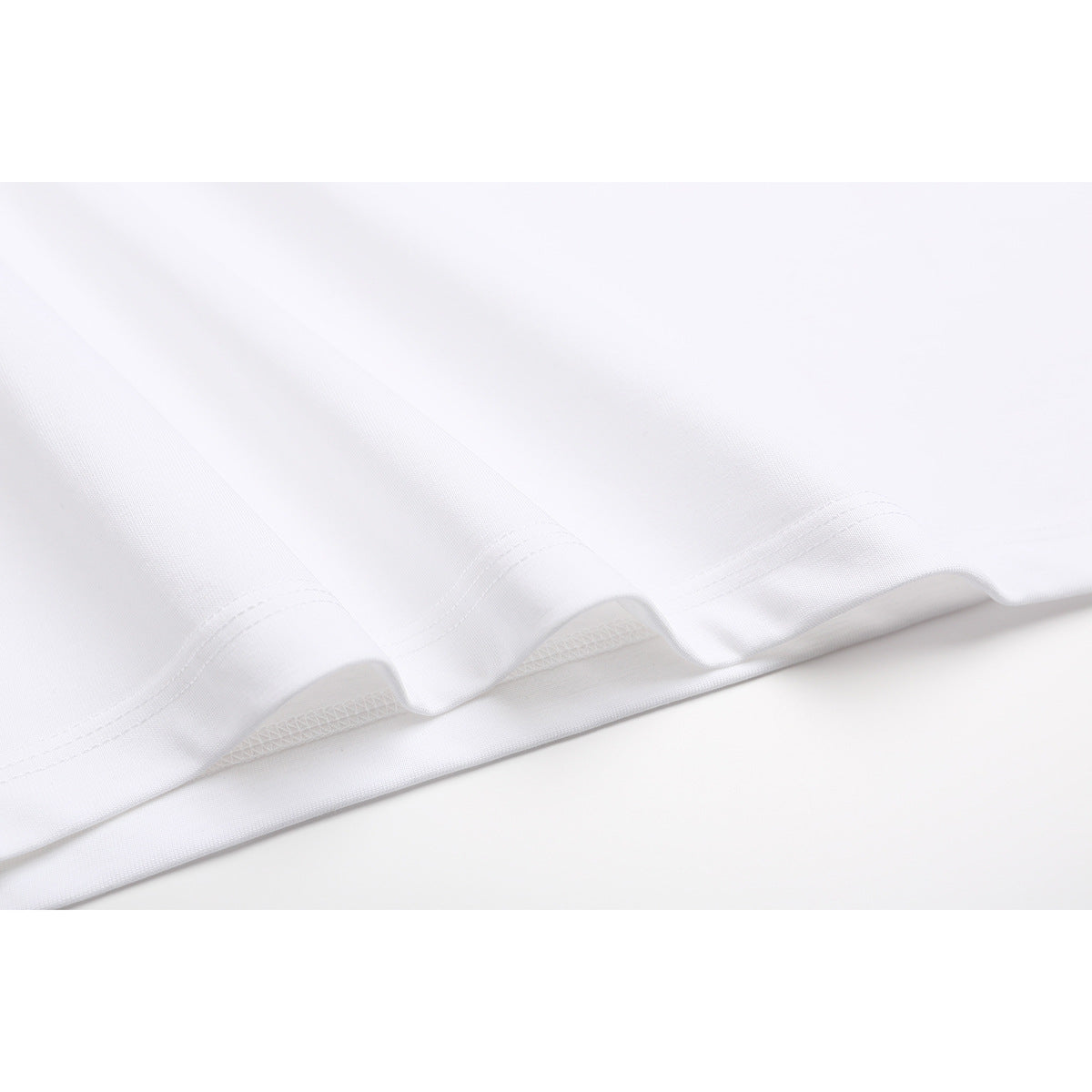 Close-up of the white T-shirt’s wavy lower hem and stitching.