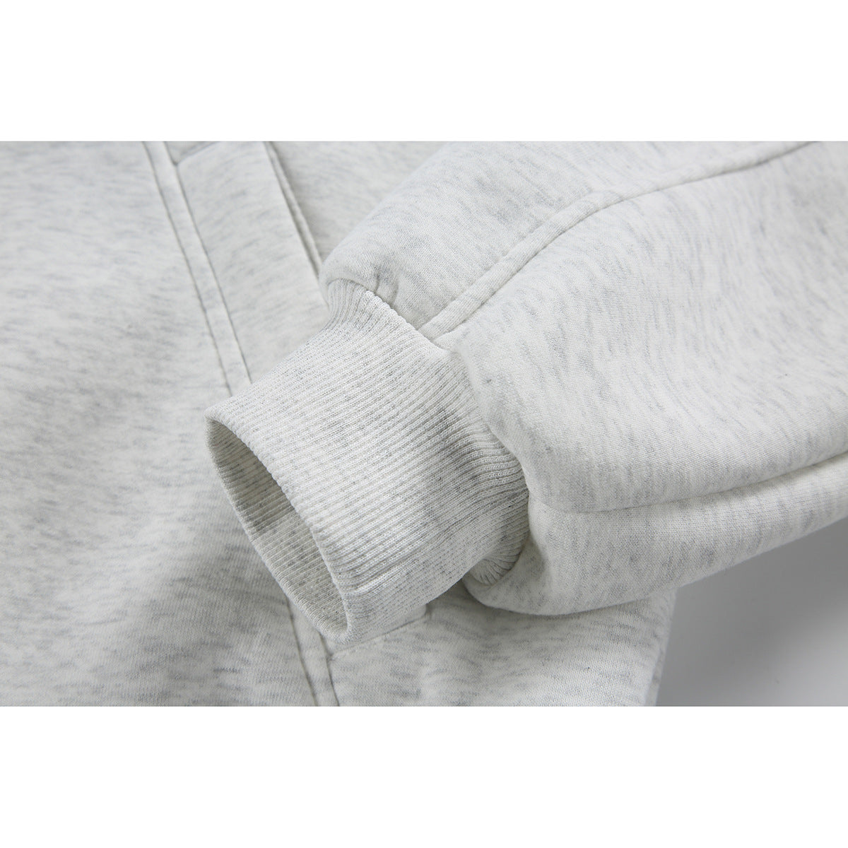 Close-up of a light gray jacket sleeve and ribbed cuff with visible stitching and panel seams.