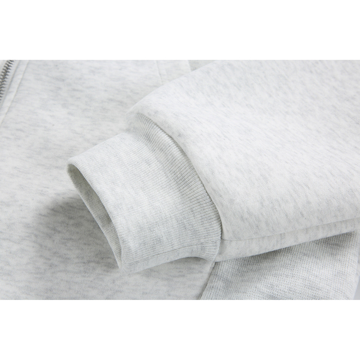 Close-up of the light gray heather hoodie’s ribbed sleeve cuff and fabric.