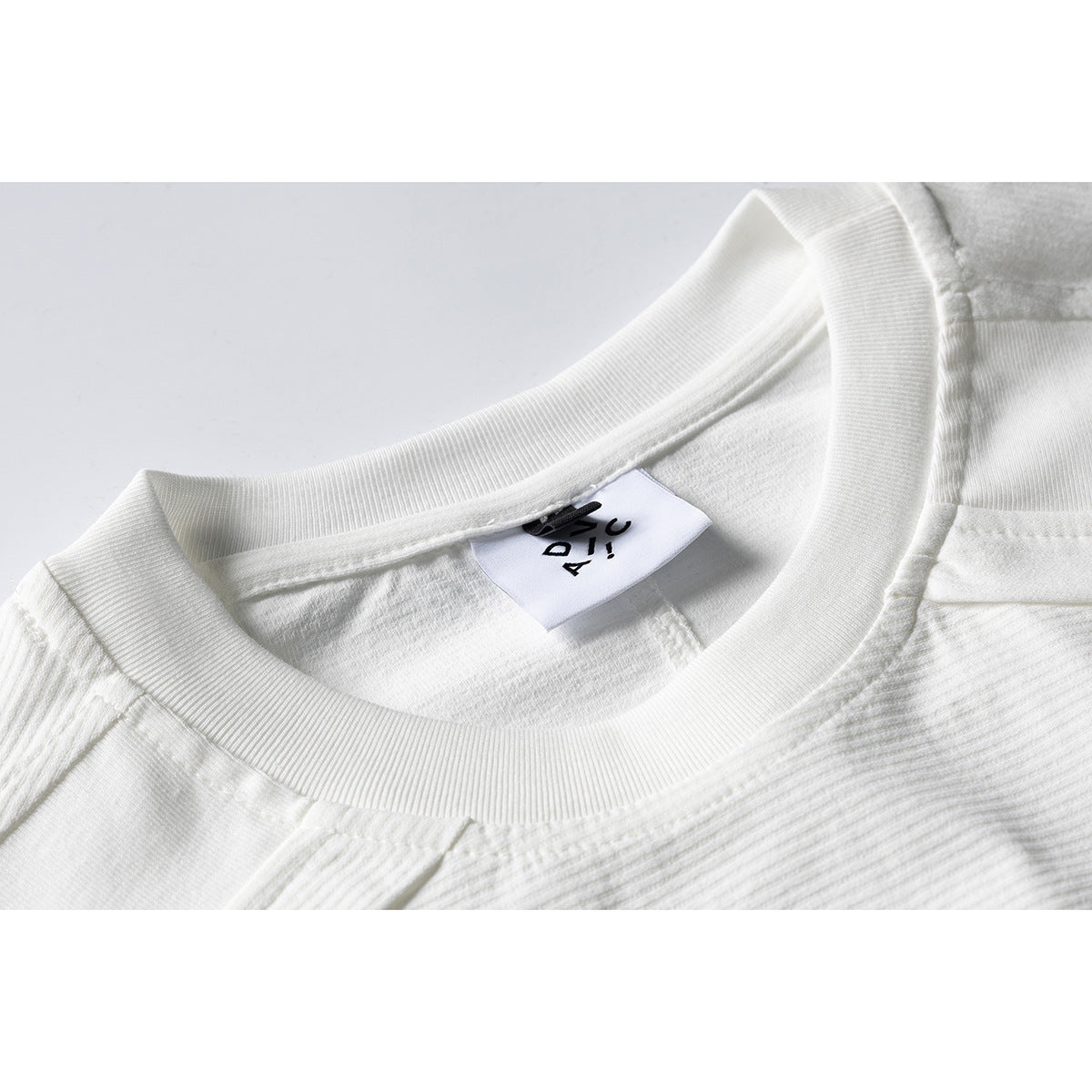 Close-up of a white ribbed crew neck and inner label with black lettering.