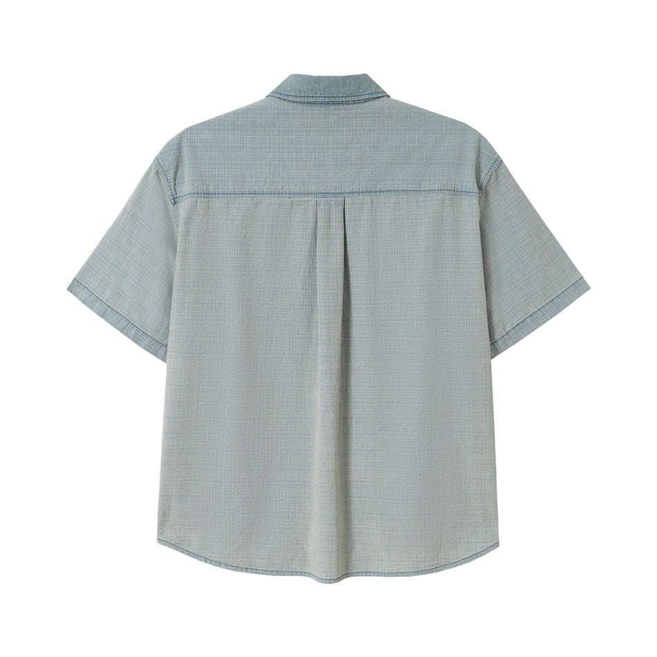 Back view of washed blue short-sleeve shirt with yoke seam and center pleat, flat lay