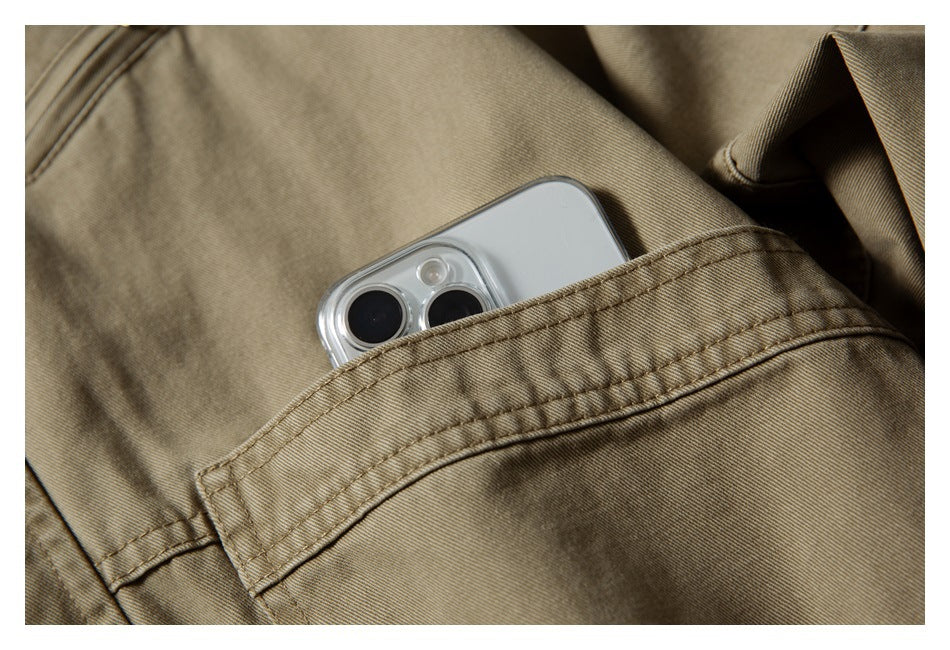 Close-up of a phone tucked into a stitched pocket on a khaki jacket.