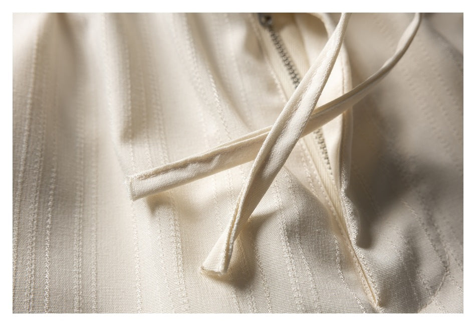 Close-up of cream striped trousers showing the front zipper and narrow drawstrings.