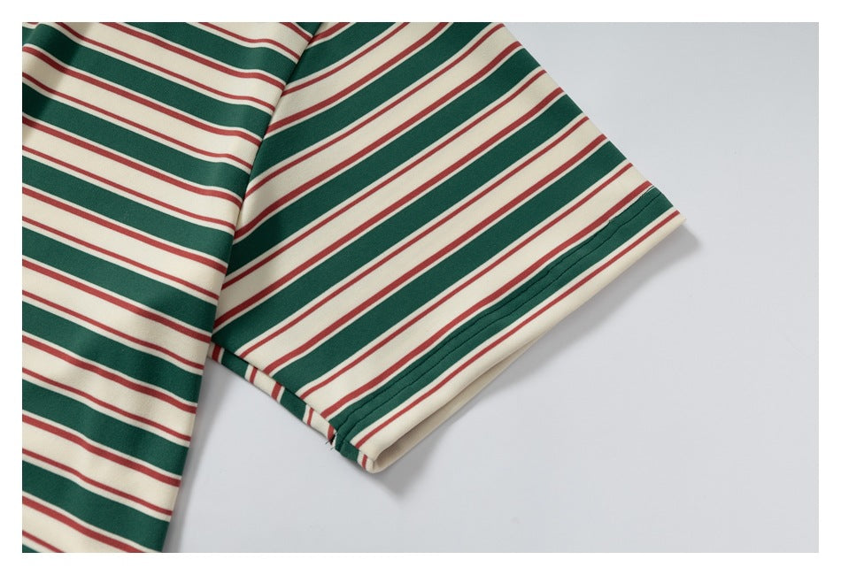 Close-up of a short sleeve hem on a cream shirt with dark green and thin red horizontal stripes.