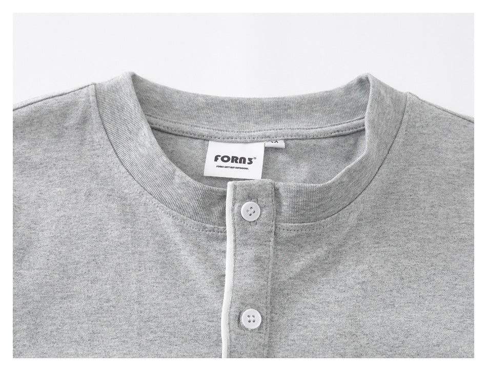 Close-up of a gray T-shirt's crew neckline, two-button placket, and sewn neck label.