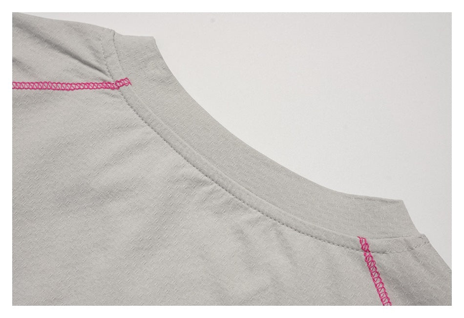 Close-up of a light gray shirt neckline with bright pink seam stitching.