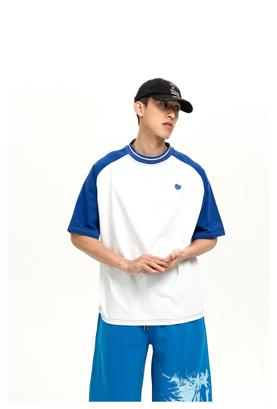 Closer front view of a model wearing a white T-shirt with blue raglan sleeves and blue pants with a horse graphic.