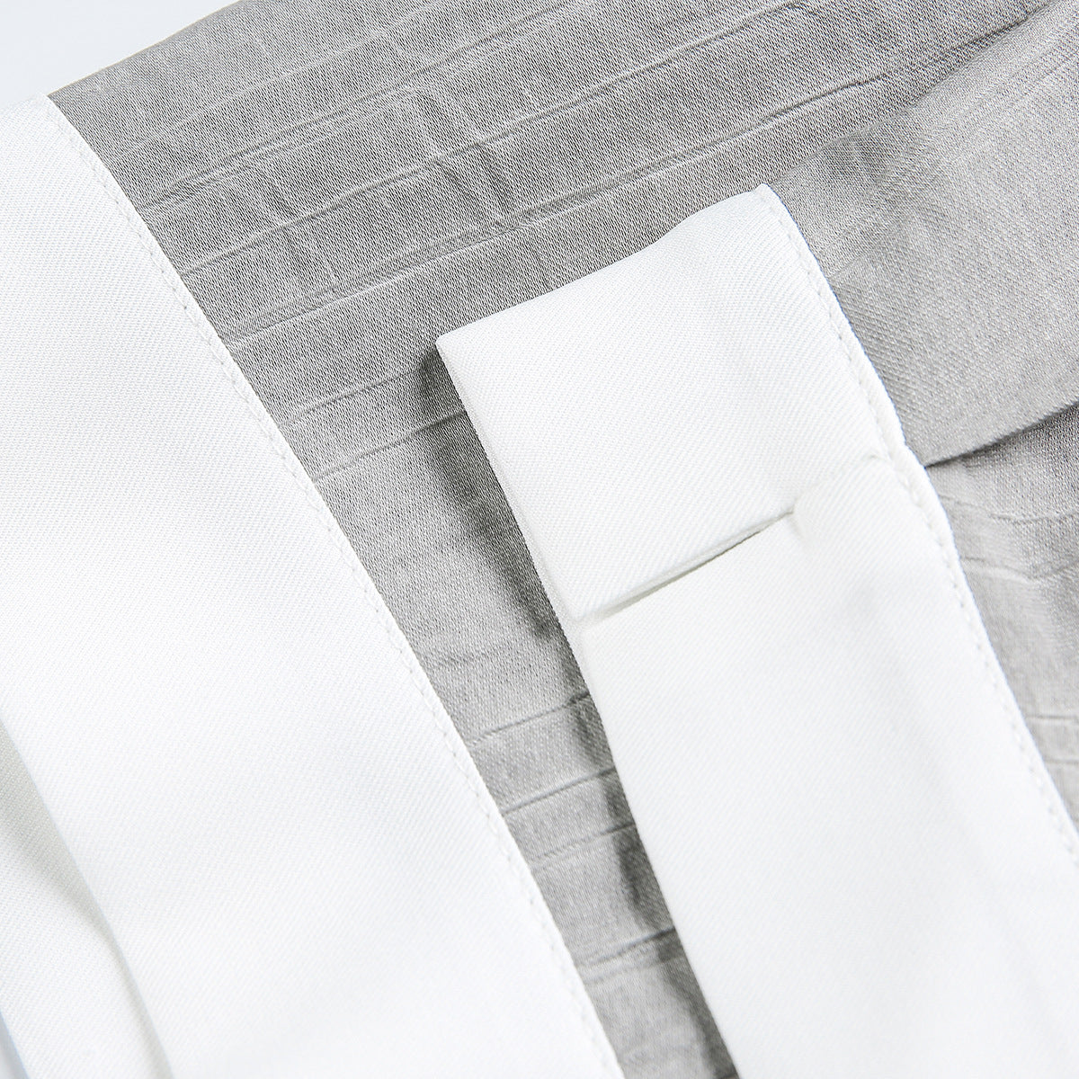 Close-up of a white shirt cuff against gray striped fabric.