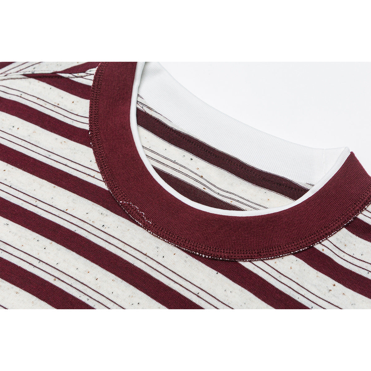 Close-up of a burgundy ribbed crew neck and cream fabric with burgundy stripes.