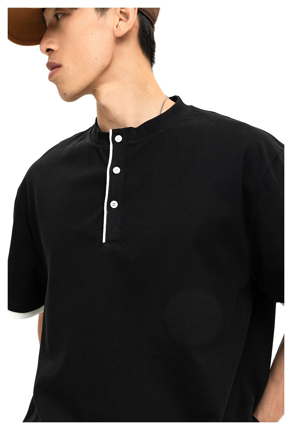 Close-up of a black Henley shirt showing its band collar, three white buttons, and white sleeve trim.