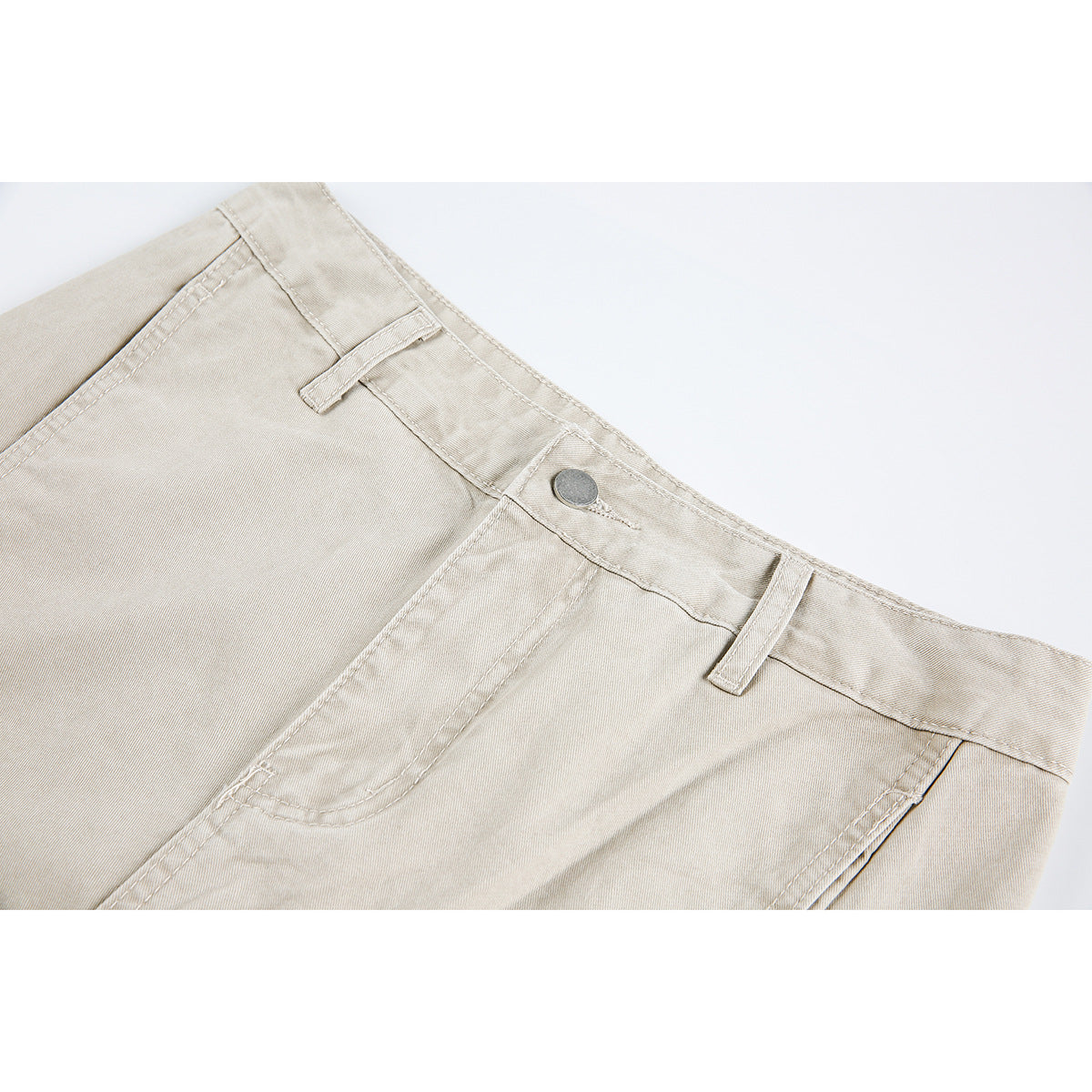 Close-up of light beige trousers showing the waistband, belt loops, metal button, and front pocket.