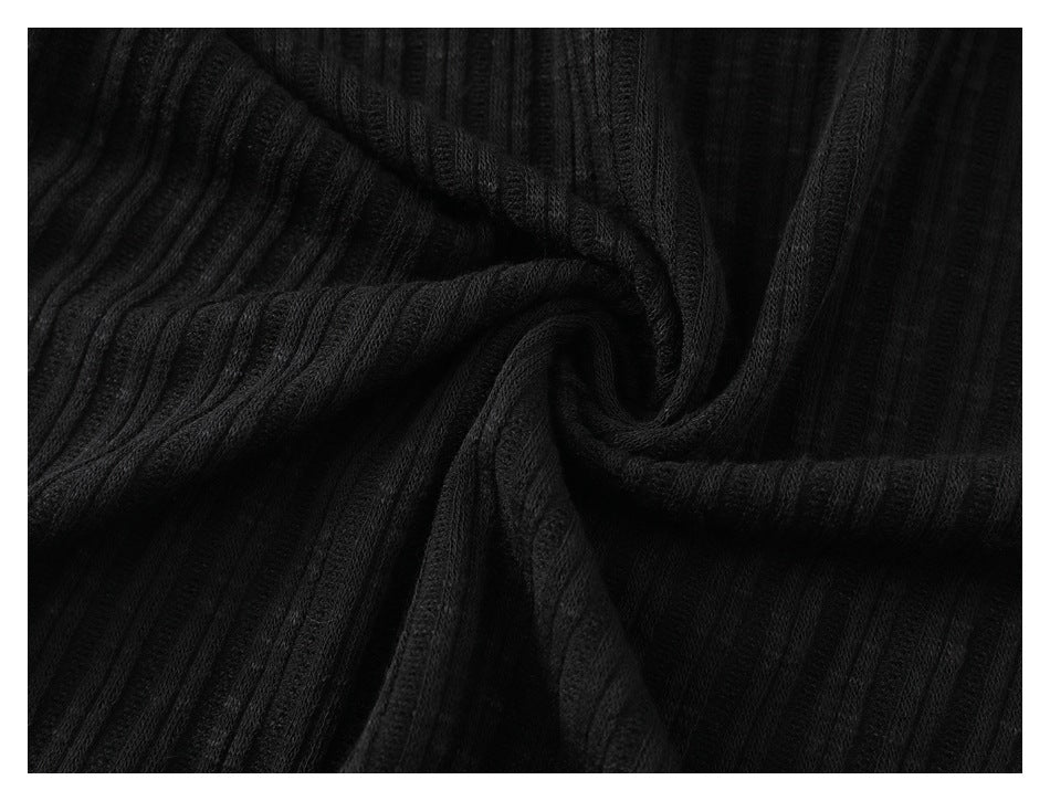 Close-up of black ribbed fabric gathered into a swirl, showing its texture.