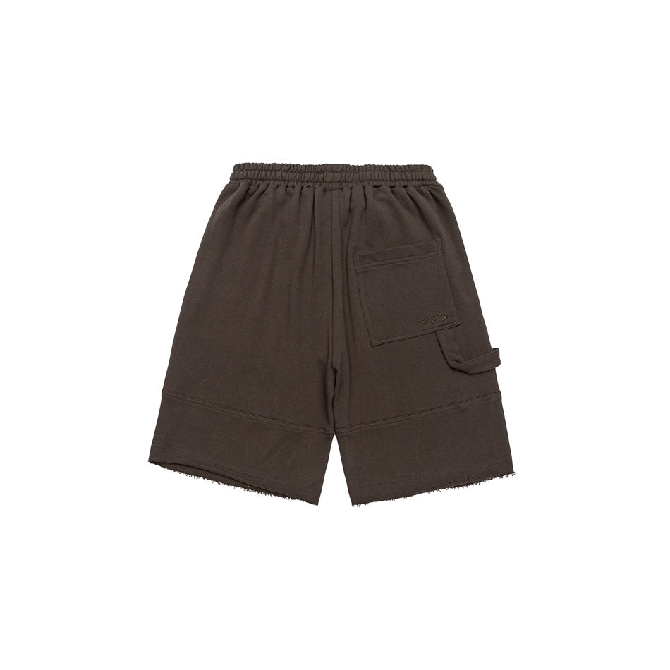 Back view of brown shorts with an elastic waist, patch pocket, side strap, and raw hems.