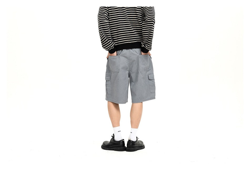 Rear view of a person wearing light gray cargo shorts with a black-and-cream striped top, white socks, and black shoes.