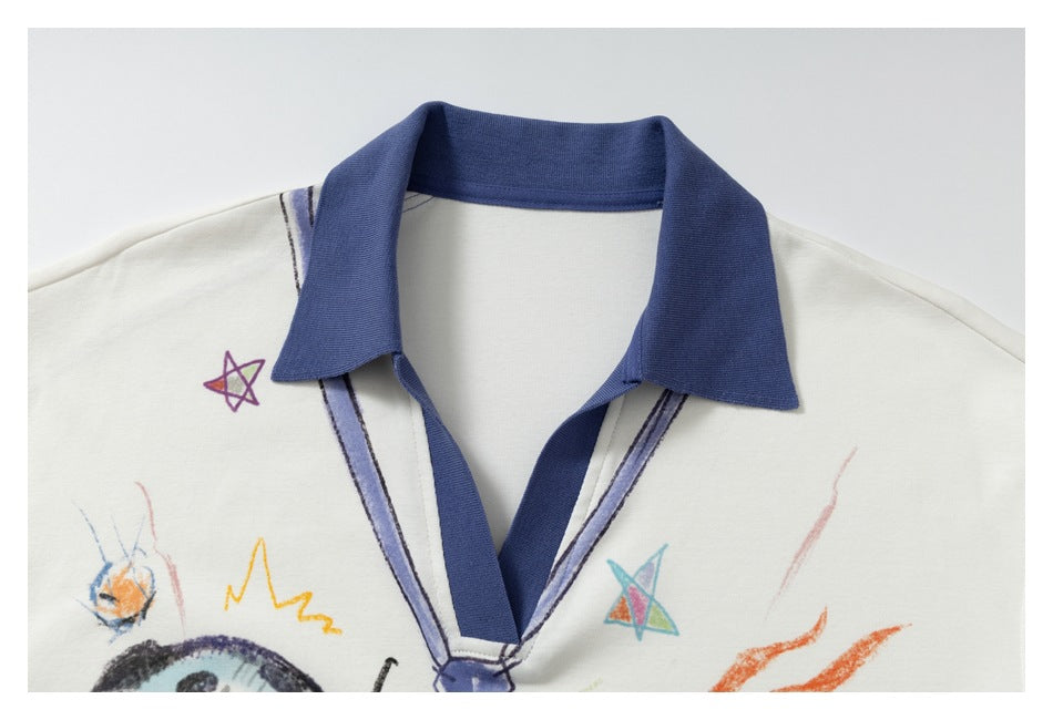 Close-up of the ivory polo's blue collar and V-neck, with colorful doodles visible on the chest.