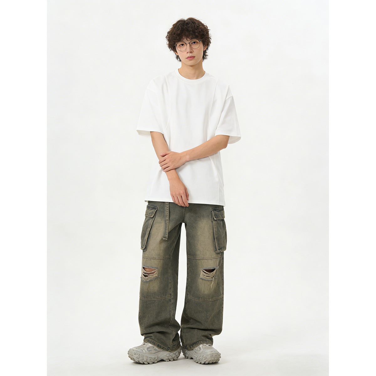 Model wearing an oversized white short-sleeve T-shirt with olive-gray distressed cargo pants.