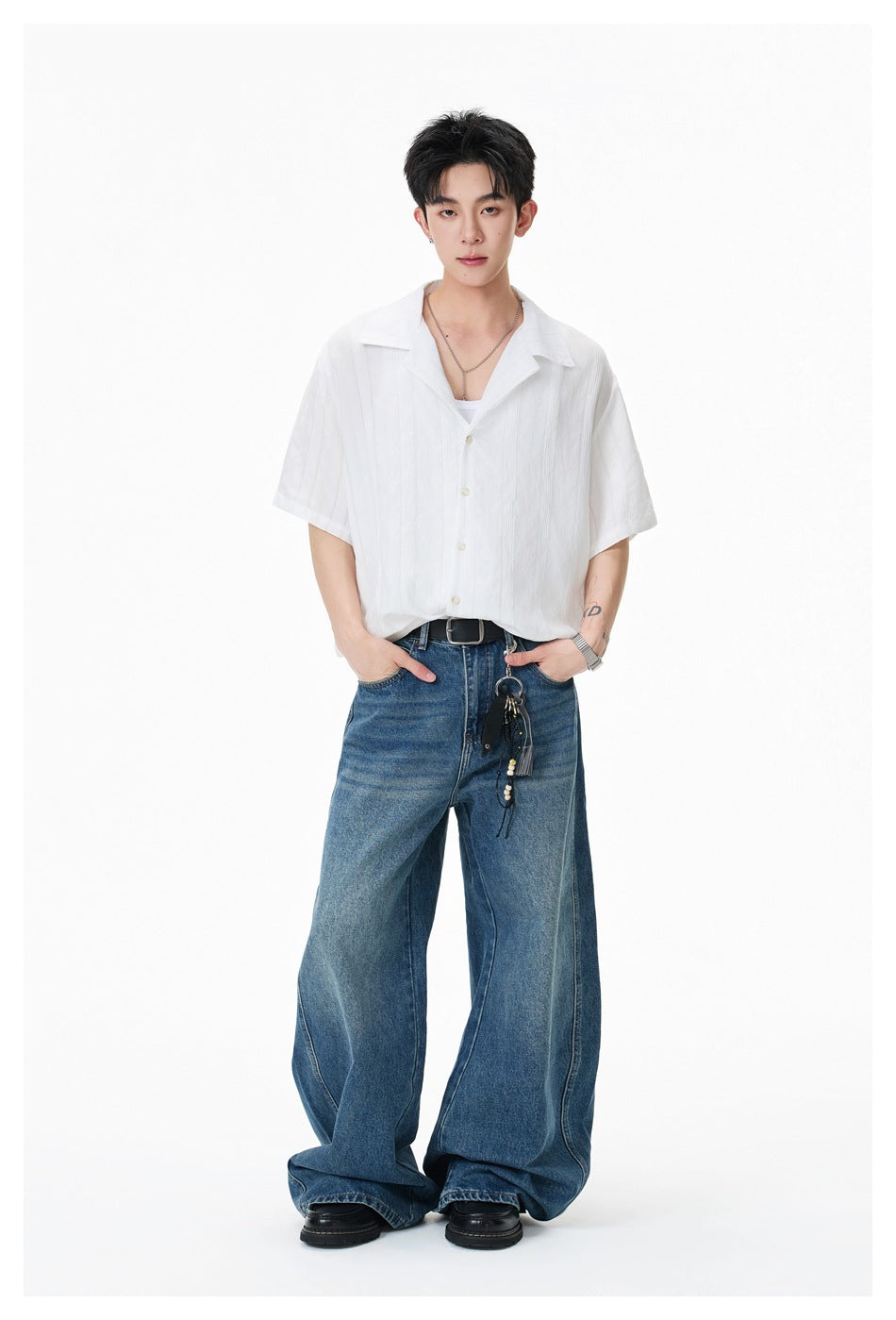 Model wearing a white short-sleeve collared shirt with blue wide-leg jeans, shown full length from the front.