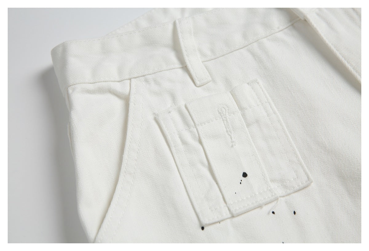 Close-up of a small stitched utility pocket on white pants, with a few black specks nearby.