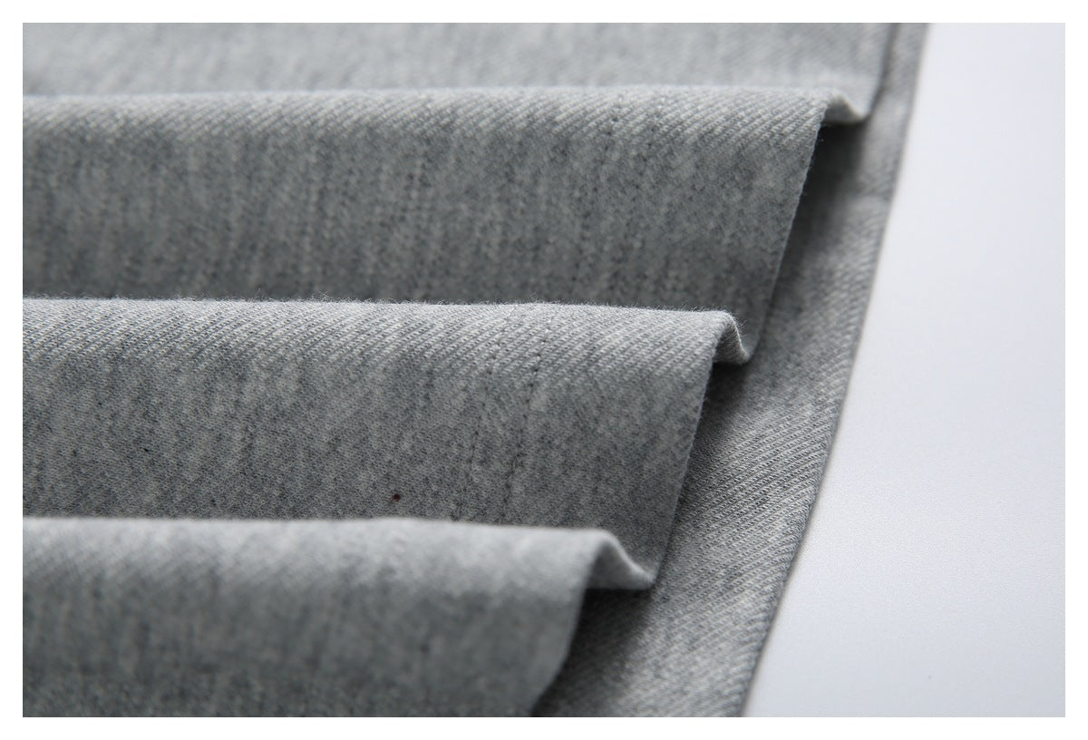 Close-up of gray garment fabric arranged in layered folds, showing the edge stitching.
