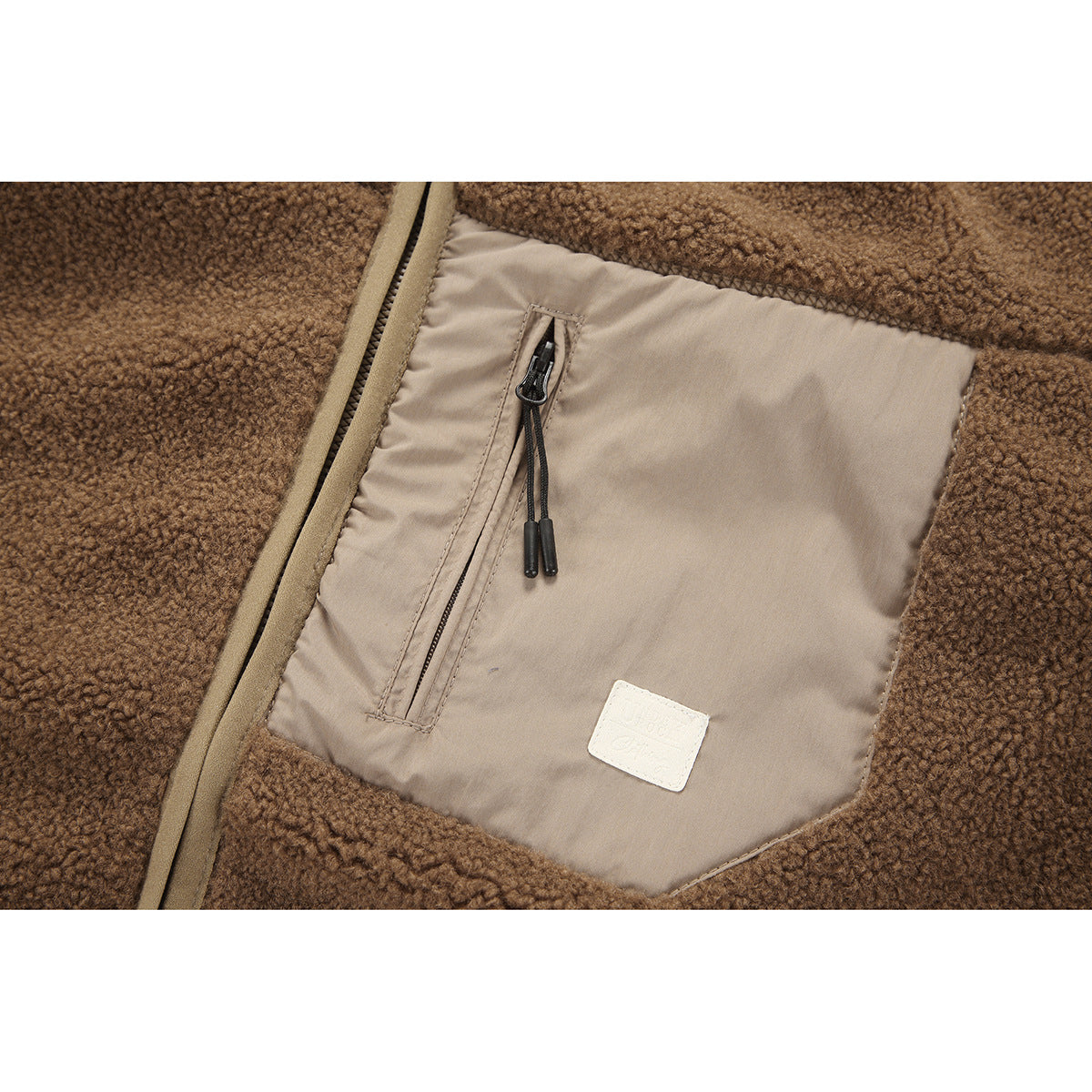 Close-up of a tan-lined pocket with a vertical zipper on a brown textured fleece jacket.