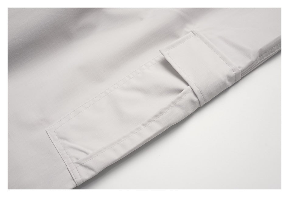 Close-up of light gray pants showing a rectangular side pocket and stitched cuff.