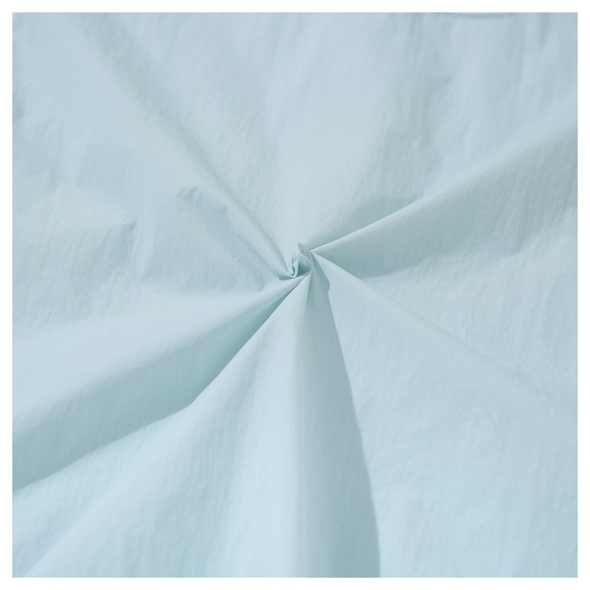 Close-up of pale mint fabric gathered at the center to show its surface and drape.