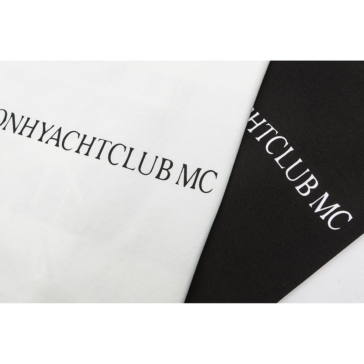 Close-up of printed lettering on overlapping off-white and black T-shirts.