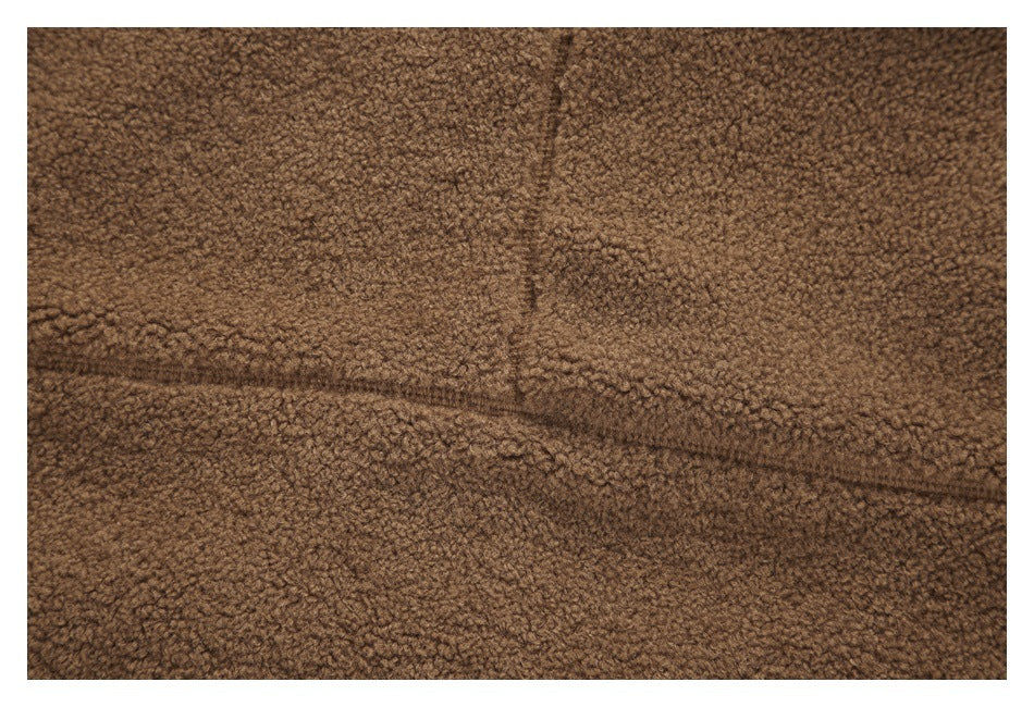 Close-up of stitching and seams on brown curly-textured fabric.