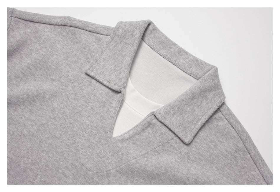 Close-up of a light gray top's pointed collar and V-shaped neckline, showing a white layer underneath.