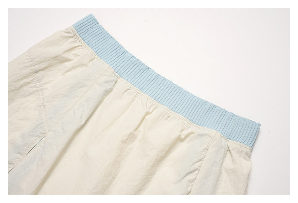 Close-up of the cream skirt’s gathered top edge and wide, ribbed light-blue waistband.