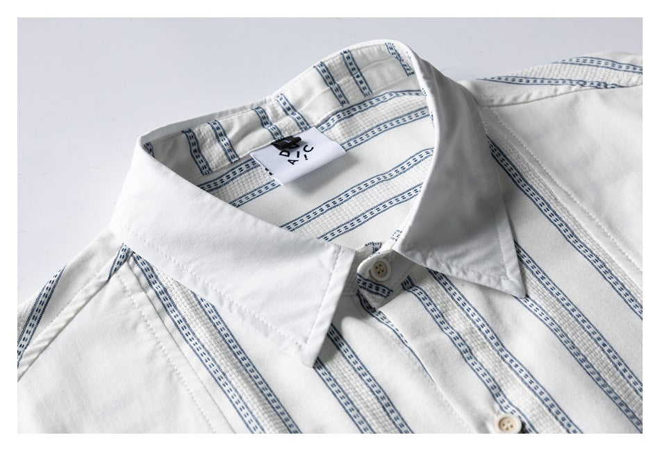 Close-up of a white shirt collar and placket with narrow blue patterned stripes and a visible neck label.