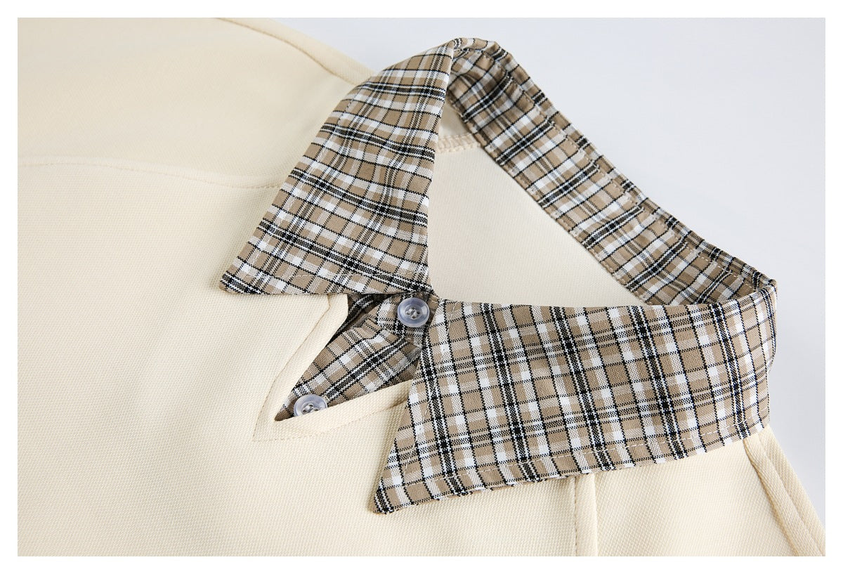 Close-up of a cream garment's beige, black, and white plaid collar and buttoned neckline.