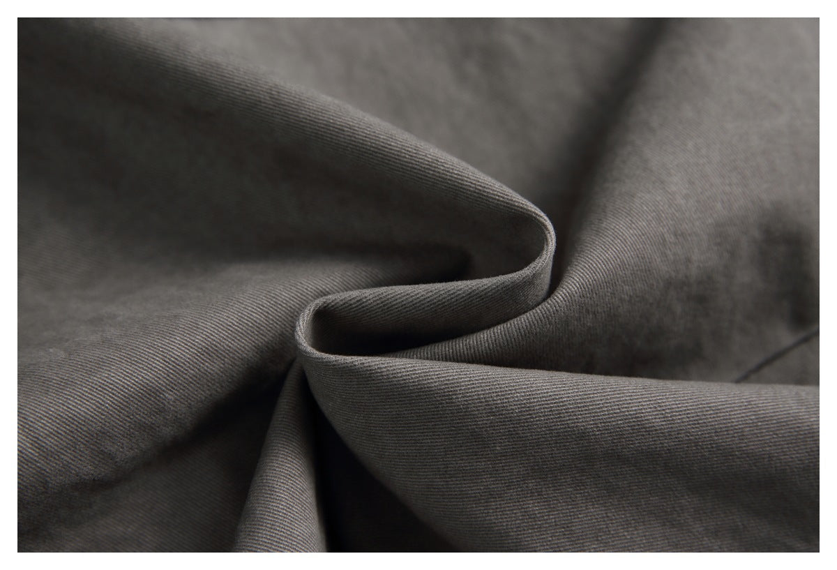 Macro view of charcoal-gray fabric folded to show its fine diagonal weave.