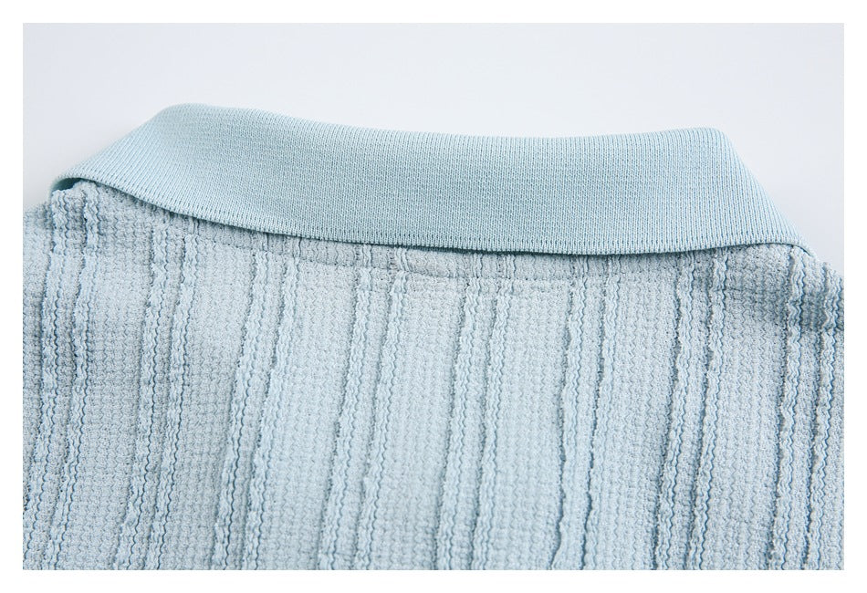 Close-up of a pale blue garment collar above raised vertical textured fabric.