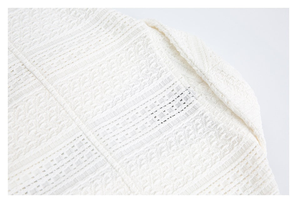 Close-up of white textured knit with openwork bands and a folded edge.
