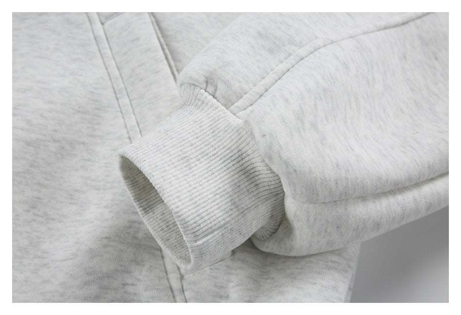 Close-up of the ribbed cuff and sleeve seam on a light gray marled jacket.